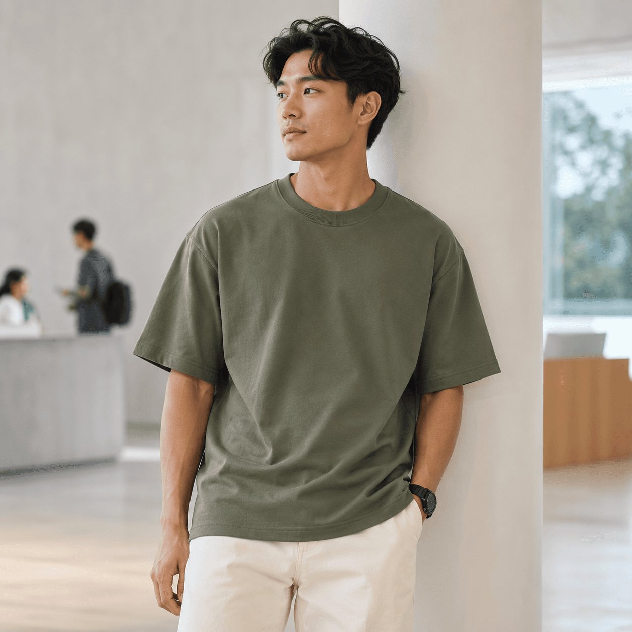 Team member wearing a sage green custom company T-shirt in a modern office setting.